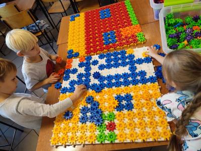 Uczniowie układają domek z różnych figur geometrycznych.