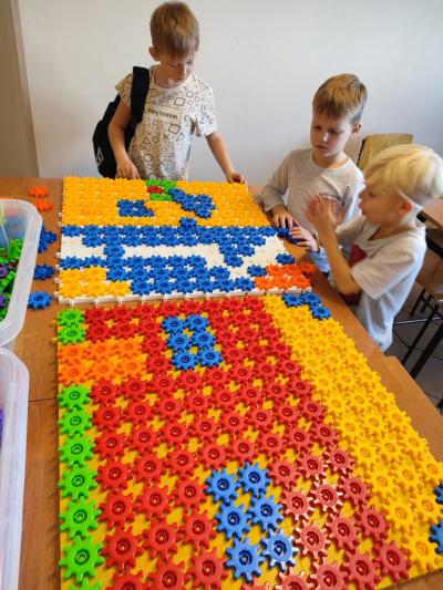 Uczniowie układają domek z różnych figur geometrycznych.