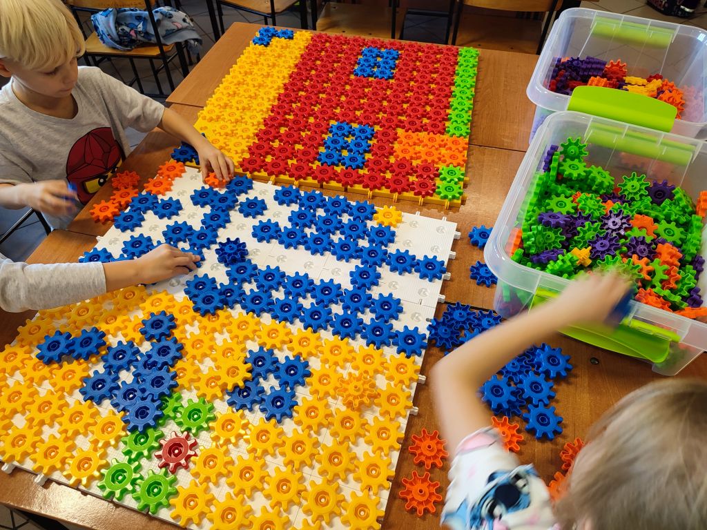 Uczniowie układają domek z różnych figur geometrycznych.