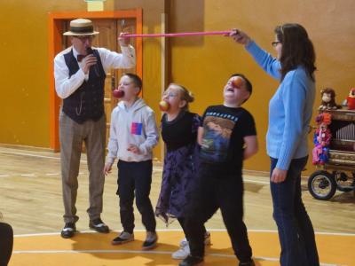 Zabawa andrzejkowa w jedzenie jabłek zawieszonych na sznurkach.