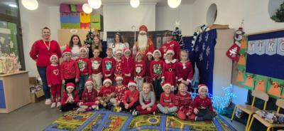 Grupa Skrzaty pozuje do zdjęcia z Mikołajem.