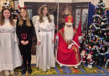 Święty Mikołaj z dwoma aniołkami i diabełkiem pozują do zdjęcia.