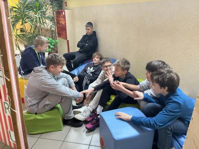 uczniowie podczas przerwy siedzą na miękkich pufach w strefie komfortu na szkolnym korytarzu