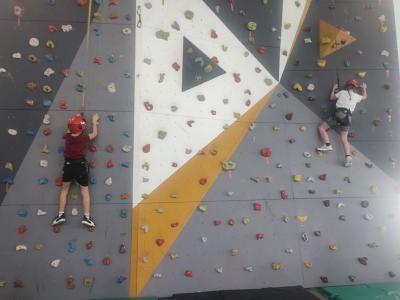 Dzieci biorą udział w zajęciach sportowych w hali sportowej na ściance wspinaczkowej.