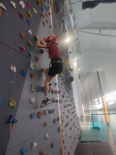 Dzieci biorą udział w zajęciach sportowych w hali sportowej na ściance wspinaczkowej.