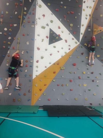 Dzieci biorą udział w zajęciach sportowych w hali sportowej na ściance wspinaczkowej.