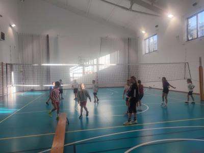 Dzieci biorą udział w zajęciach sportowych w hali sportowej na ściance wspinaczkowej.