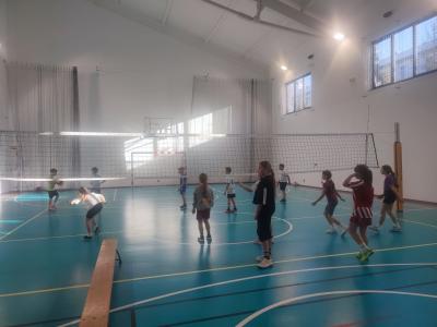 Dzieci biorą udział w zajęciach sportowych w hali sportowej na ściance wspinaczkowej.