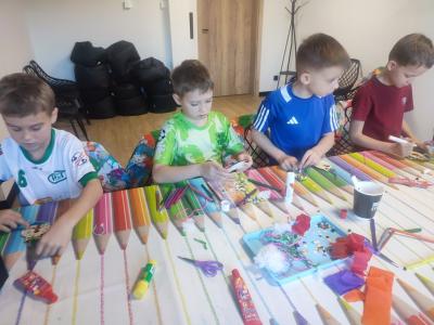 Uczniowie siedzą przy stoliku podczas warsztatów plastycznych