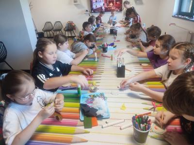 Uczniowie siedzą przy stoliku podczas warsztatów plastycznych