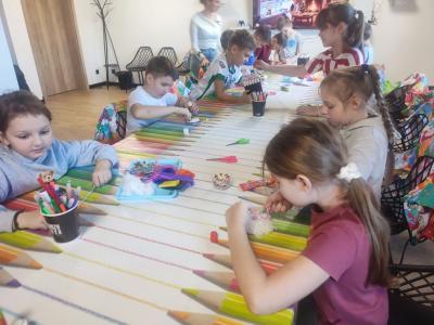 Uczniowie siedzą przy stoliku podczas warsztatów plastycznych