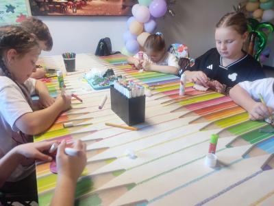 Uczniowie siedzą przy stoliku podczas warsztatów plastycznych