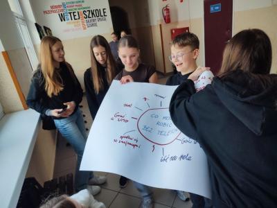 Uczniowie zbierający wpisy na plakat co można robić bez telefonu