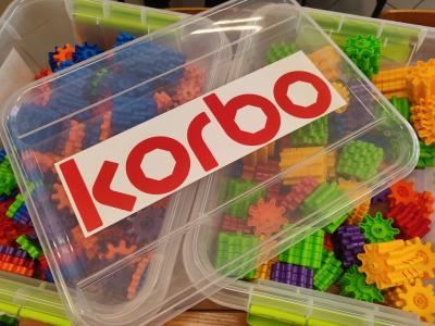 Pudełko kolorowych klocków wraz z pokrywką i napisem Korbo