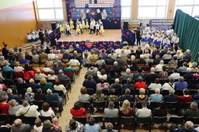 Zdjęcie z balkonu na gości w hali sportowej i występujące na scenie przedszkolaki