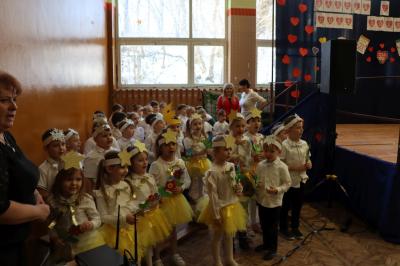 Przedszkolaki stojące przy scenie, śpiewają sto lat, w rękach trzymają upominki dla dziadków