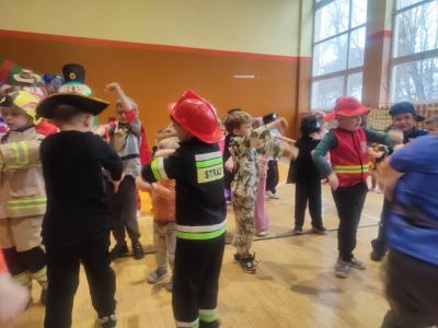 Przedszkolaki tańczą podczas zabawy karnawałowej w hali sportowej