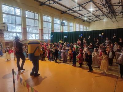 Przedszkolaki tańczą podczas zabawy karnawałowej w hali sportowej