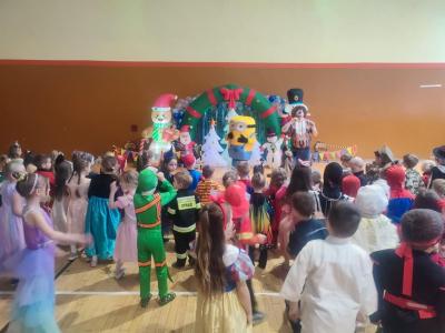 Przedszkolaki tańczą podczas zabawy karnawałowej w hali sportowej