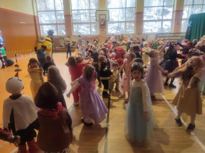 Przedszkolaki tańczą podczas zabawy karnawałowej w hali sportowej