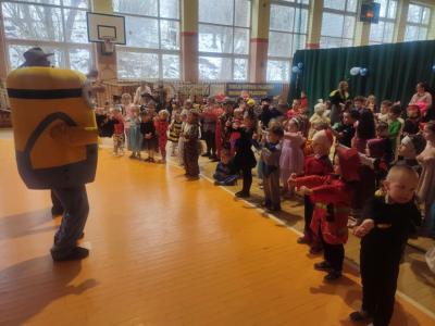 Przedszkolaki tańczą podczas zabawy karnawałowej w hali sportowej