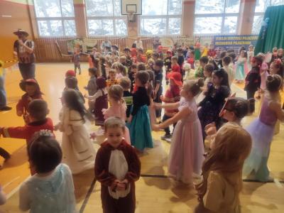 Przedszkolaki tańczą podczas zabawy karnawałowej w hali sportowej