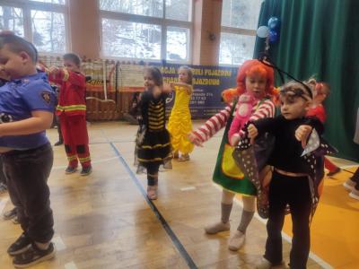 Przedszkolaki tańczą podczas zabawy karnawałowej w hali sportowej