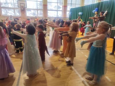 Przedszkolaki tańczą podczas zabawy karnawałowej w hali sportowej