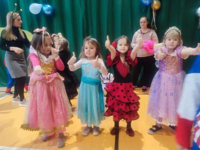 Przedszkolaki tańczą podczas zabawy karnawałowej w hali sportowej