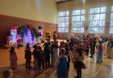 Przedszkolaki tańczą podczas zabawy karnawałowej w hali sportowej