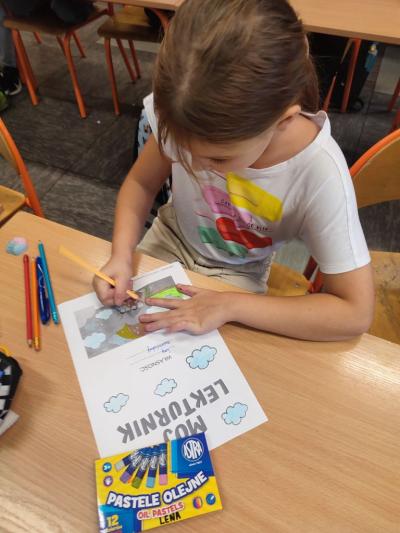 Uczniowie pracują przy stolikach w klasie szkolnej