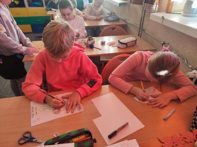 Uczniowie pracują przy stolikach w klasie szkolnej