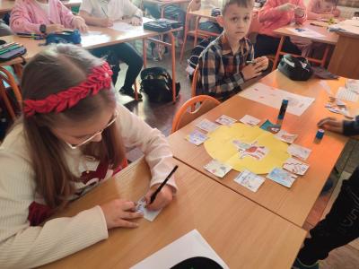 Uczniowie pracują przy stolikach w klasie szkolnej