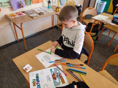 Uczniowie pracują przy stolikach w klasie szkolnej