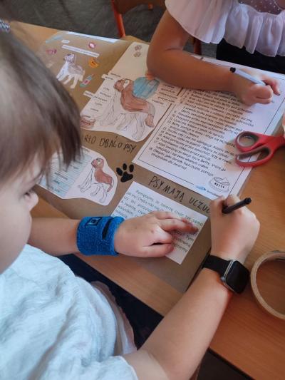 Uczniowie pracują przy stolikach w klasie szkolnej