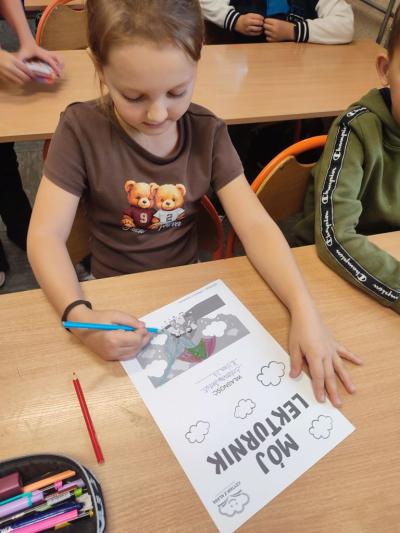 Uczniowie pracują przy stolikach w klasie szkolnej