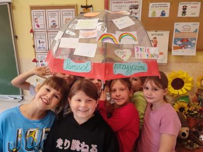 Uczniowie stoją pod parasolem