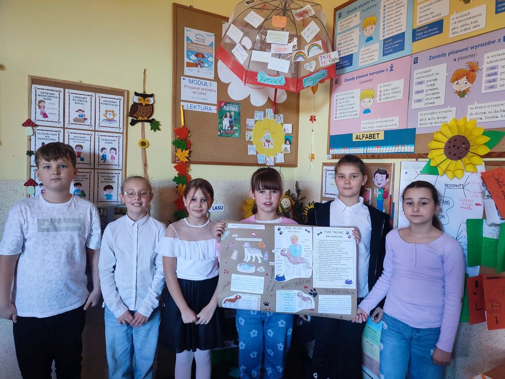 Uczniowie pozują do zdjecia, trzymają plakat.