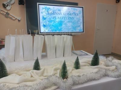 udekorowany stół chionkami za nimi białe papierowe torby w tle napis gminny konkurs plastyczny.