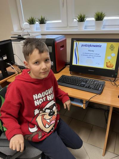 Chłopiec pozuje do zdjęcia na tle zbobytego certyfikatu