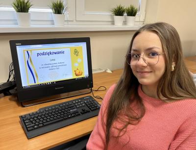 Uczennica pozuje do zdjęcia na tle zbobytego certyfikatu