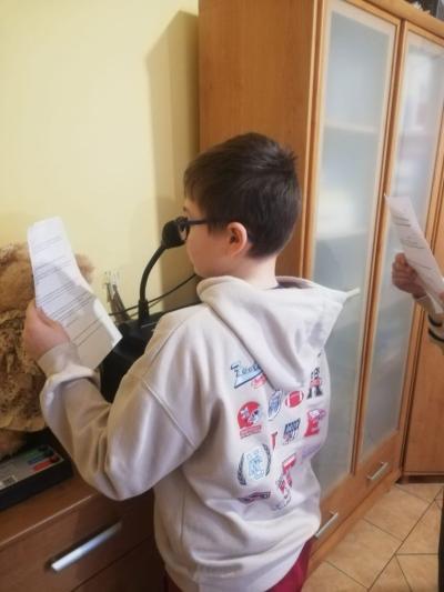 uczniowie czytają tekst przez radiowęzeł szkolny