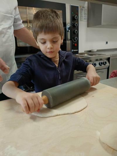 Chłopiec wałkuje ciasto na pizzę.