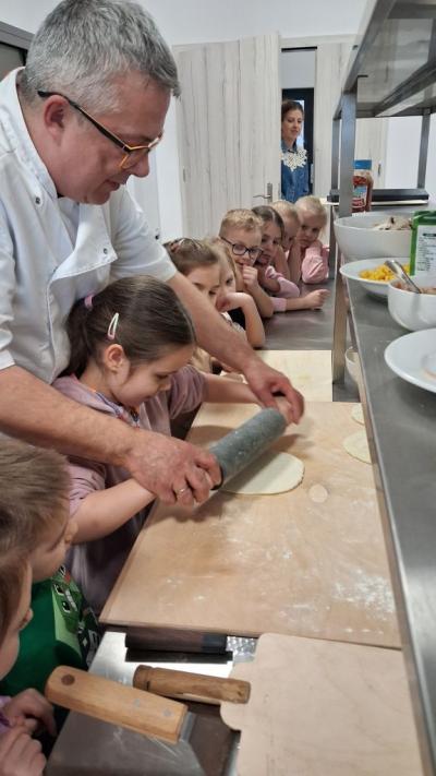 Dziewczynka wałkuje ciasto na pizze.