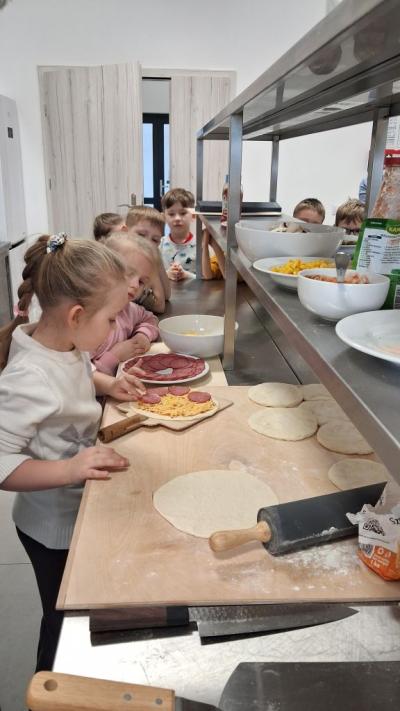 układa składniki na pizze