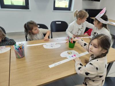 Dziewczynki przy stolikach ozdabiają kredkami