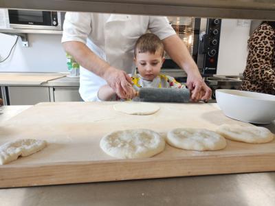 Chłopiec wałkuje ciasto na pizze.