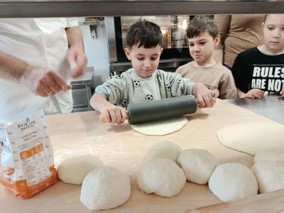Dzieci przyglądają się jak ich kolega samodzielnie wałkuje ciasto.