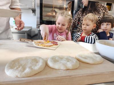 Dziewczynka dodaje kukurydzę do pizzy.