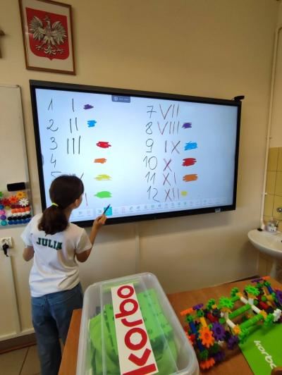 Uczniowie pracujący na klockach Korbo z wykozrystaniem cyfr rzymskich wykorzystanych do budowy planszy zegara